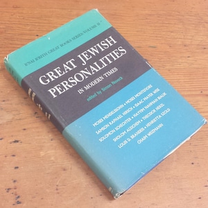 May include: A blue and black book titled "Great Jewish Personalities in Modern Times" edited by Simon Noveck. The book lists the names of prominent Jewish figures, including Moses Mendelssohn, Samson Raphael Hirsch, Isaac Mayer Wise, and Chaim Weizmann.
