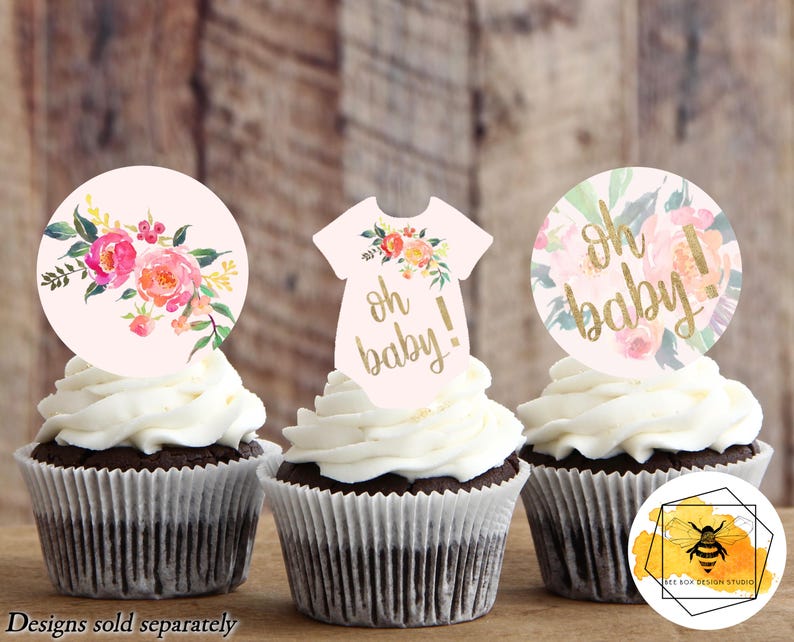 K&ouml;nnte beinhalten: Drei Cupcake-Topper mit einem rosa-goldenen Blumendesign. Die Topper zeigen den Text "Oh Baby!" und einen Baby-Strampler.
