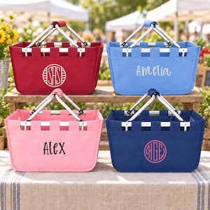 May include: Four rectangular collapsible market baskets with silver metal handles. The top left is red with a white circular monogram. The top right is light blue with the white text Amelia. The bottom left is pink with the black text Alex. The bottom right is navy blue with a pink circular monogram.