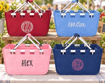 May include: Four rectangular collapsible market baskets with silver metal handles. The top left is red with a white circular monogram. The top right is light blue with the white text Amelia. The bottom left is pink with the black text Alex. The bottom right is navy blue with a pink circular monogram.