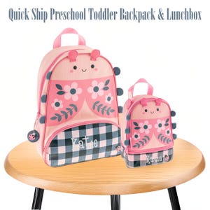 May include: A pink backpack and matching lunchbox set featuring a ladybug-inspired design with floral patterns, black and white checkered base, and the name Katie printed on the front. Both items have small antennae and side accents.