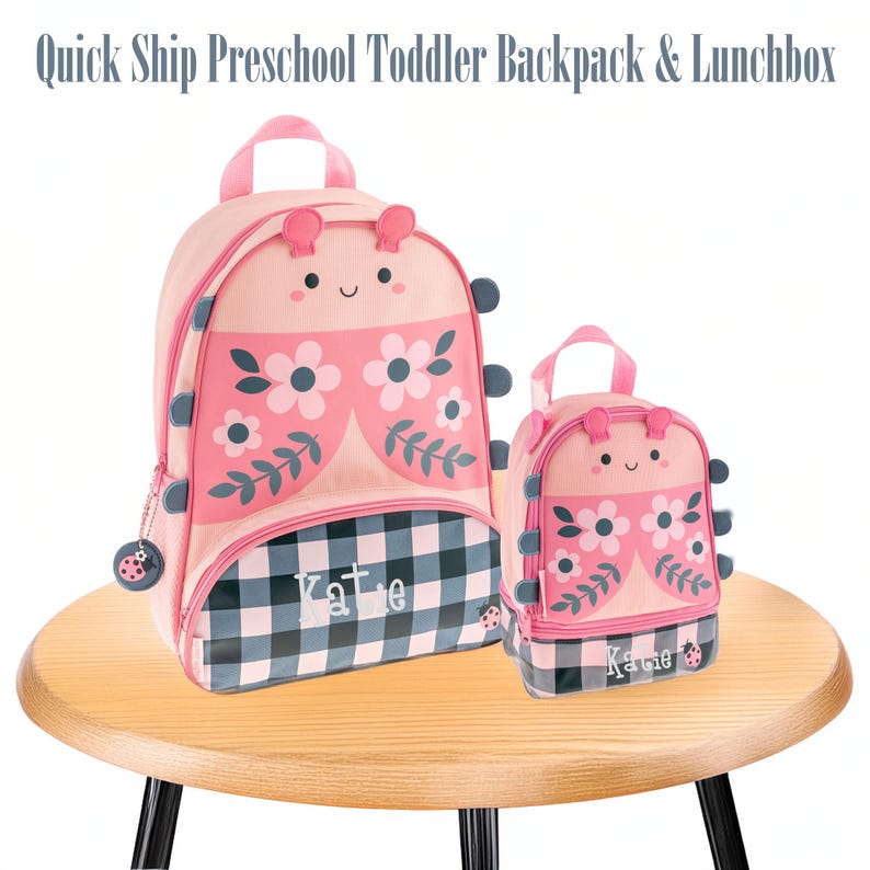 May include: A pink backpack and matching lunchbox set featuring a ladybug-inspired design with floral patterns, black and white checkered base, and the name Katie printed on the front. Both items have small antennae and side accents.