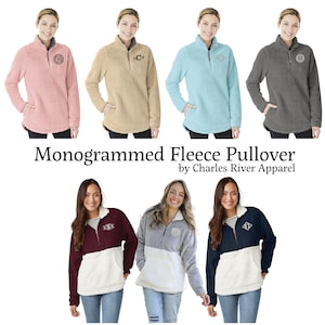 May include: A collection of monogrammed fleece pullovers in various colors, including pink, tan, blue, and gray. The pullovers have a quarter-zip neckline, a front pocket, and a monogram on the chest. The text "Monogrammed Fleece Pullover by Charles River Apparel" is displayed.