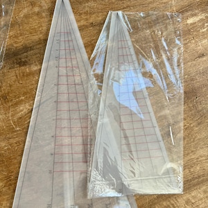 May include: Two clear plastic triangle rulers with black and red markings. The rulers are marked in inches up to 30 inches.