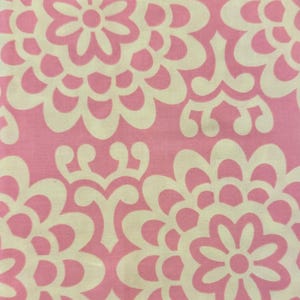 Peut inclure: Gros plan sur un motif floral rose et blanc. Le motif présente de grandes fleurs stylisées et des formes tourbillonnantes dans un motif répétitif. Le fond est rose clair et les fleurs sont blanches.