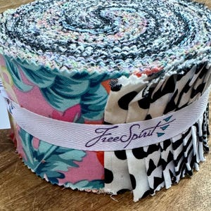 Peut inclure: Un rouleau de tissu présentant une variété d'imprimés, notamment des motifs floraux, animaliers et géométriques. Le tissu est enveloppé d'un ruban blanc sur lequel est imprimé le texte "Free Spirit". Le tissu est 100% coton et lavable en machine.