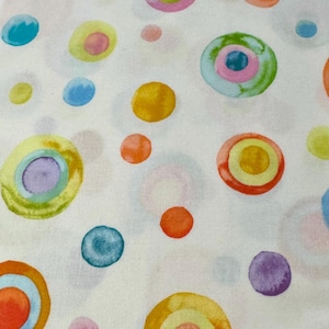 May include: White fabric with a repeating pattern of colourful circles. The circles are painted in shades of blue, green, yellow, orange, pink, and purple. Some of the circles have a concentric ring pattern.