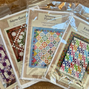 May include: Four quilting patterns for table runners and quilts. The patterns are titled "Hunter's Star Pointed Table Runner", "Snowflurri", "Spinning Pinwheels", and "Fanfare".