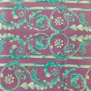 Pode incluir: Close-up de um tecido com um padrão repetitivo de desenhos florais e de rolagem turquesa sobre um fundo roxo. O design inclui listras horizontais e pequenos motivos florais. O tecido está rotulado como "Westminster Fibers # TG25 L".