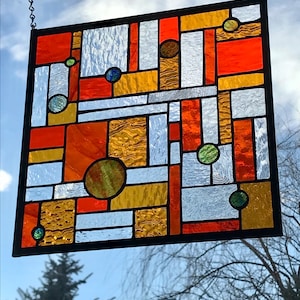 May include: A stained glass window with a geometric design featuring orange, yellow, and green squares and circles.