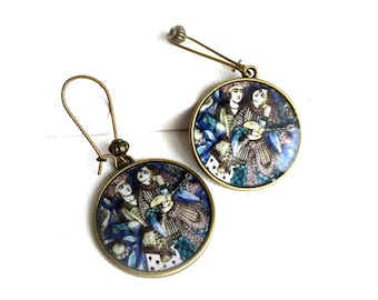 Può includere: Un paio di orecchini rotondi con un'illustrazione dettagliata di figure in abiti tradizionali. Gli orecchini hanno una montatura in metallo color oro e una chiusura a gancio. L'illustrazione utilizza toni blu, viola e marroni.