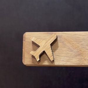 Puede incluir: Un recorte de avión de madera sobre una superficie de madera marrón claro.
