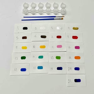 May include: A set of 21 paint colors in small containers, labeled with numbers 1 through 21. The colors include black, white, silver, gold, brown, red, yellow, pink, green, turquoise, orange, and blue.