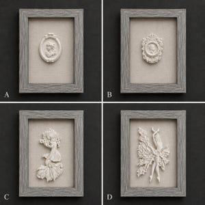 May include: Four rectangular wall frames with grey wood-grain finish, each containing a beige fabric backing and a white relief sculpture. The sculptures depict a profile cameo, a crowned cameo, a mermaid figure, and a dancing figure with flowing fabric.
