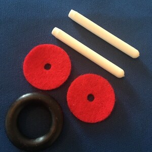 May include: Two white dowel rods, two red felt circles with a black center hole, and a black rubber ring. These are parts for a toy.