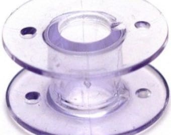 May include: A clear plastic bobbin for a sewing machine.