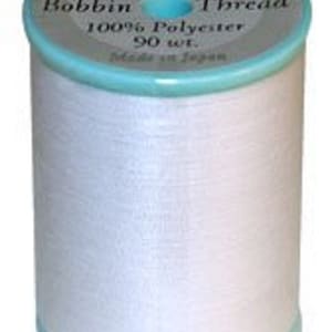 May include: A spool of white bobbin thread with a light blue rim and top. The label reads "The Finishing Touch Bobbin Thread 100% Polyester 90 wt. Made in Japan."