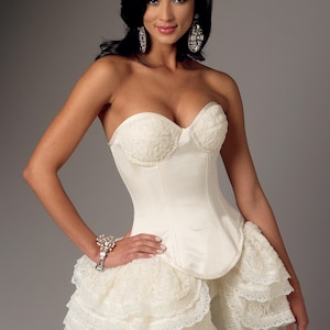 Op de afbeelding: Een witte strapless corset met een kant overlay en een geruite rok. De corset heeft een beenderen structuur en een gladde satijnen afwerking. De rok is gemaakt van lagen delicate kant.