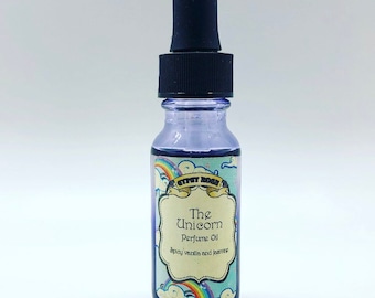 May include: A small glass bottle with a dropper top filled with a purple liquid. The bottle has a colorful label that reads "The Unicorn Perfume Oil Spicy vanilla and jasmine".