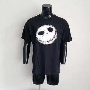 K&ouml;nnte beinhalten: Schwarzes T-Shirt mit einem wei&szlig;en Aufdruck von Jack Skellingtons Gesicht aus dem Film Nightmare Before Christmas.