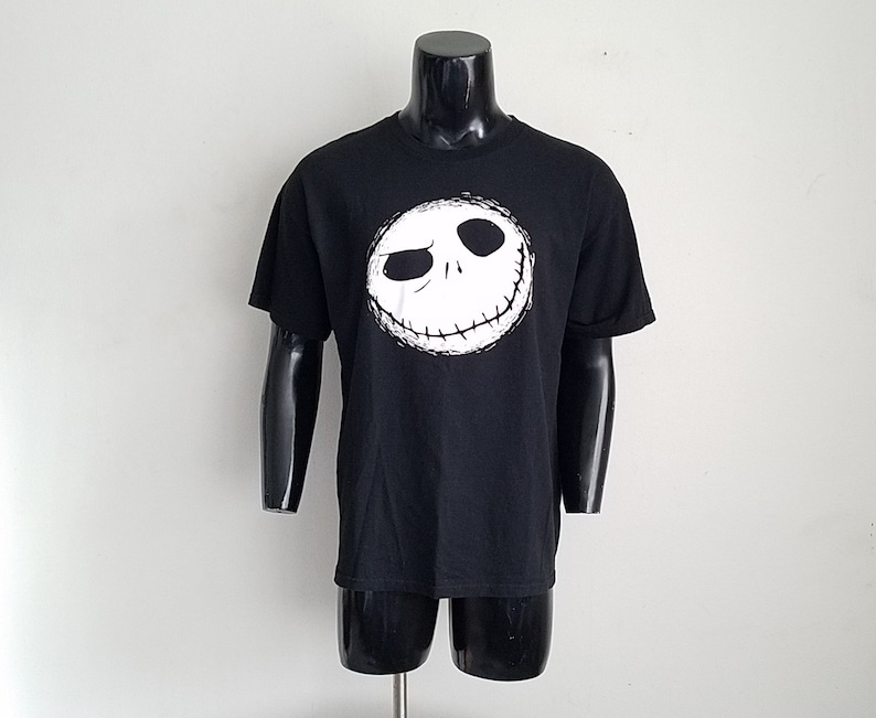 K&ouml;nnte beinhalten: Schwarzes T-Shirt mit einem wei&szlig;en Aufdruck von Jack Skellingtons Gesicht aus dem Film Nightmare Before Christmas.