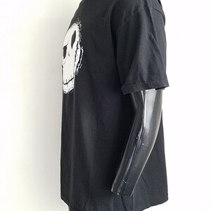 K&ouml;nnte beinhalten: Schwarzes T-Shirt mit einem wei&szlig;en Aufdruck von Jack Skellingtons Gesicht aus dem Film "Nightmare Before Christmas".