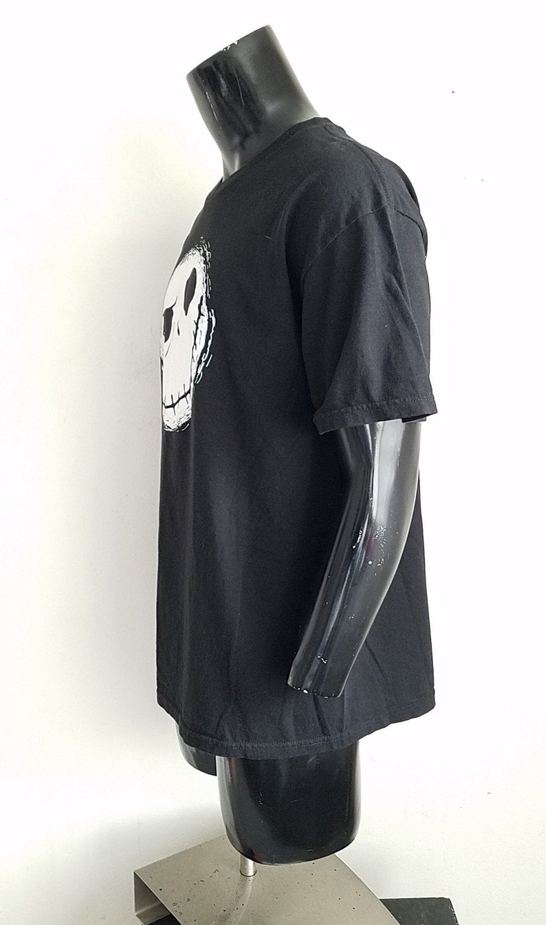 K&ouml;nnte beinhalten: Schwarzes T-Shirt mit einem wei&szlig;en Aufdruck von Jack Skellingtons Gesicht aus dem Film "Nightmare Before Christmas".