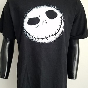 K&ouml;nnte beinhalten: Schwarzes T-Shirt mit einem wei&szlig;en Aufdruck von Jack Skellingtons Gesicht aus dem Film Nightmare Before Christmas.