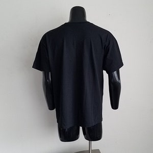 K&ouml;nnte beinhalten: Schwarzes T-Shirt mit kurzen &Auml;rmeln auf einer Puppe.