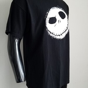 K&ouml;nnte beinhalten: Schwarzes T-Shirt mit einem wei&szlig;en Aufdruck von Jack Skellingtons Gesicht aus dem Film Nightmare Before Christmas.