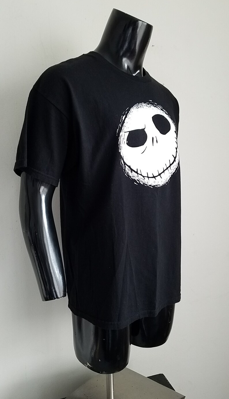 K&ouml;nnte beinhalten: Schwarzes T-Shirt mit einem wei&szlig;en Aufdruck von Jack Skellingtons Gesicht aus dem Film Nightmare Before Christmas.
