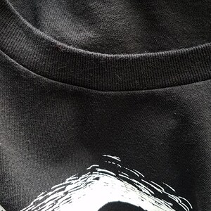 K&ouml;nnte beinhalten: Schwarzes T-Shirt mit einem wei&szlig;en Grafikdruck eines Sch&auml;dels mit einem breiten Grinsen. Der Sch&auml;del ist wei&szlig; umrandet und hat ein schwarzes Auge.