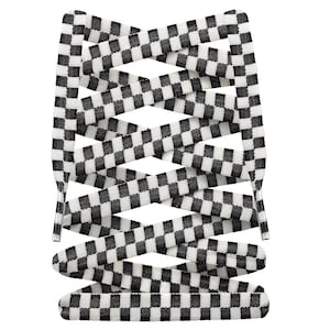 Puede incluir: Cordones de zapatos a cuadros blancos y negros. Los cordones presentan un diseño clásico de tablero de ajedrez, con cuadrados blancos y negros alternados. Los cordones están dispuestos en un patrón entrecruzado, con los extremos en la parte superior e inferior de la imagen.