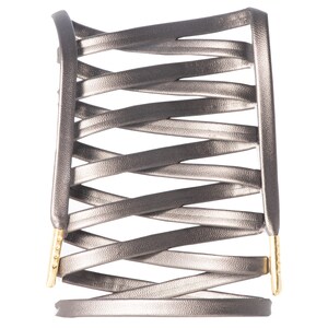 May include: A silver leather bracelet with a criss-cross design and gold accents.