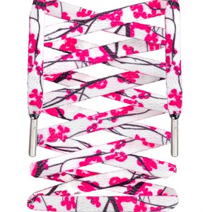 May include: White shoelaces with a pink and black floral pattern. The shoelaces are crisscrossed and tied together.