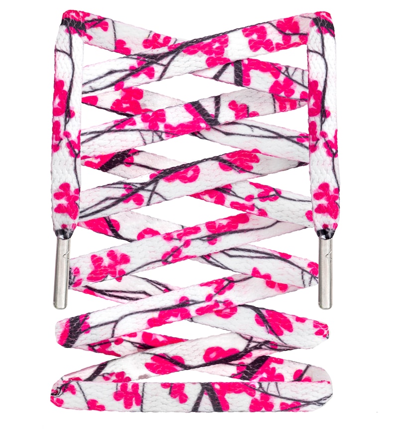 May include: White shoelaces with a pink and black floral pattern. The shoelaces are crisscrossed and tied together.