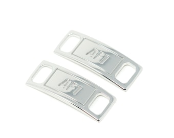 May include: Two silver metal shoe lace aglets with the text "AF1" embossed on them.