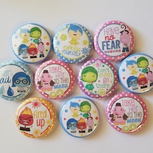 May include: A collection of nine circular pin-back buttons featuring colorful cartoon characters and text. The designs include phrases like Have no fear, Express yourself, That's sad, Take her to the moon, Don't even go there, and Fired up.