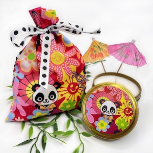 May include: A red and white fabric gift bag with a black and white polka dot ribbon. The bag features a panda bear design and colourful flowers. A small tin candle with a panda bear design and colourful flowers is also included.