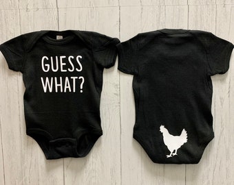 May include: Two black baby onesies. The onesie on the left has the text "GUESS WHAT?" printed in white. The onesie on the right has a white silhouette of a chicken printed on the back.