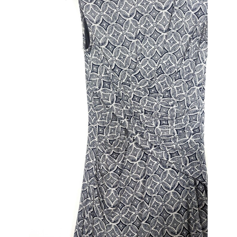 Puede incluir: Vestido sin mangas con un estampado geom&eacute;trico repetitivo en azul marino y blanco. La tela est&aacute; fruncida en la cintura, creando una silueta favorecedora. El vestido parece estar hecho de un material ligero, adecuado para el clima c&aacute;lido.
