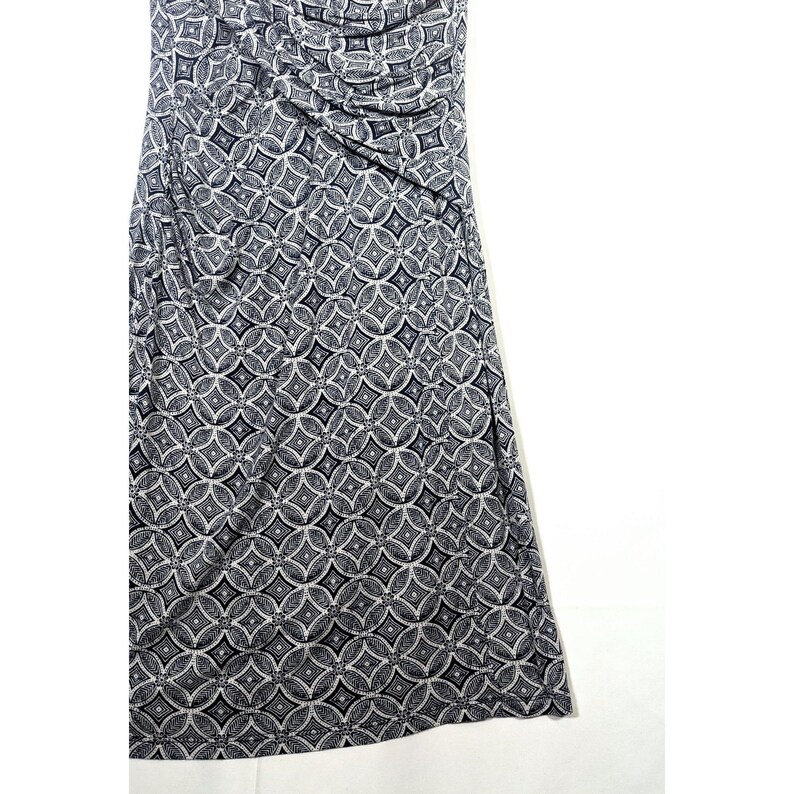 Puede incluir: Vestido sin mangas con estampado geom&eacute;trico en blanco y negro. La tela est&aacute; fruncida en el busto, creando un efecto drapeado. El vestido tiene una silueta ajustada y llega hasta la pantorrilla. El patr&oacute;n consiste en c&iacute;rculos y cuadrados entrelazados.