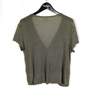 May include: Olive green V-neck short-sleeve shirt hanging on a black hanger. The shirt is made of a lightweight, semi-sheer fabric. The Polo Sport logo is visible on the hanger.