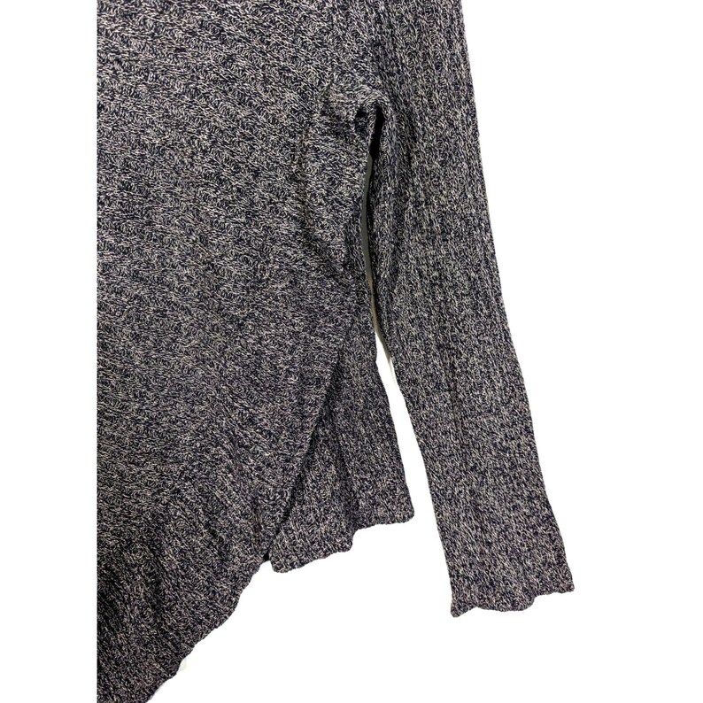 K&ouml;nnte beinhalten: Ein grau-wei&szlig; gesprenkelter Strickpullover mit Schlitzsaum und langen &Auml;rmeln. Die &Auml;rmel haben eine gerippte Textur. Der Pullover ist aus einem weichen, bequemen Material gefertigt.