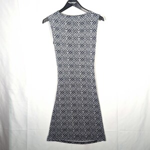 Puede incluir: Vestido sin mangas con un estampado geom&eacute;trico en tonos grises y azul marino. El vestido est&aacute; colgado de una percha negra. El estampado consiste en c&iacute;rculos y rombos entrelazados.