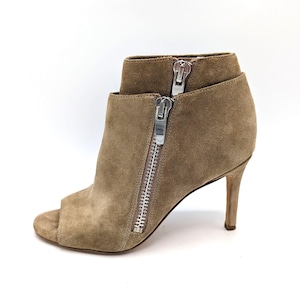 May include: A tan suede peep-toe bootie with a stiletto heel. The bootie features a silver zipper closure on the side and a second zipper on the back of the ankle. The heel measures approximately 4 inches.