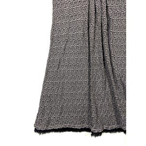 May include: A draped fabric with a wave-like pattern in black and gray. The bottom edge has a black fringe. The fabric appears to be a skirt or a piece of clothing.