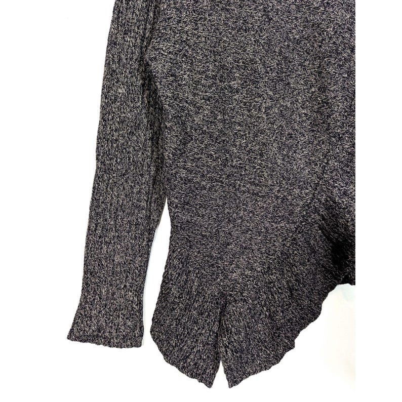K&ouml;nnte beinhalten: Ein dunkelgrau-wei&szlig; gesprenkelter Strickpullover mit einem ausgestellten, asymmetrischen Saum. Der lange &Auml;rmel hat eine ausgestellte Manschette. Der Pullover ist aus einem strukturierten Strickstoff gefertigt.