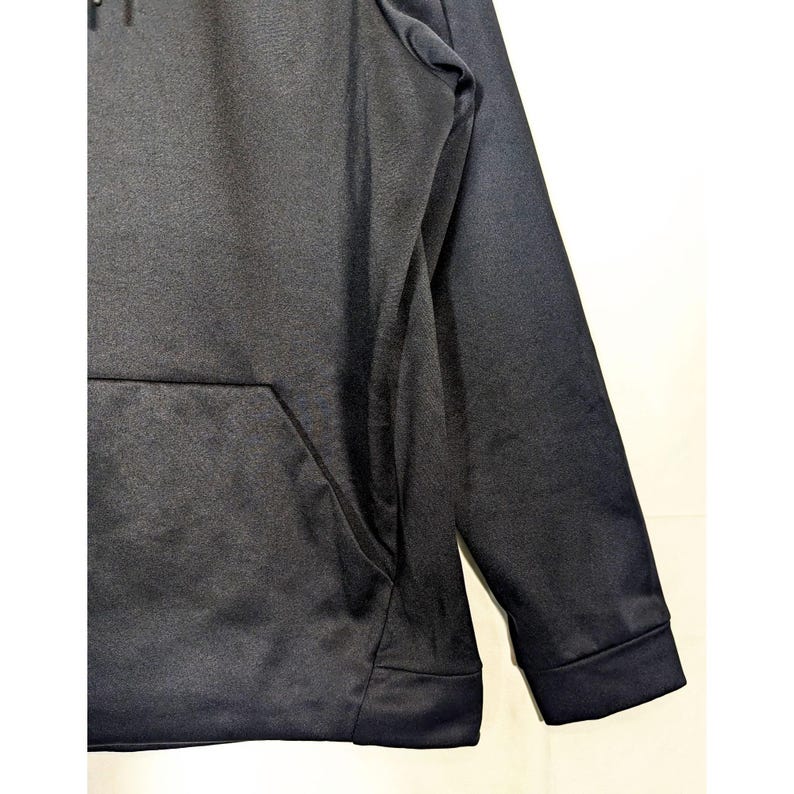 May include: A black hooded sweatshirt with a kangaroo pocket. The long sleeves have ribbed cuffs. The fabric has a subtle sheen. The hood is visible at the top of the image.