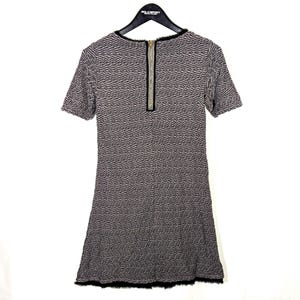 May include: A short-sleeved dress with a textured pattern in shades of gray and black. The dress features a gold zipper down the back and a black fringe at the hemline. The neckline is trimmed with black fabric.